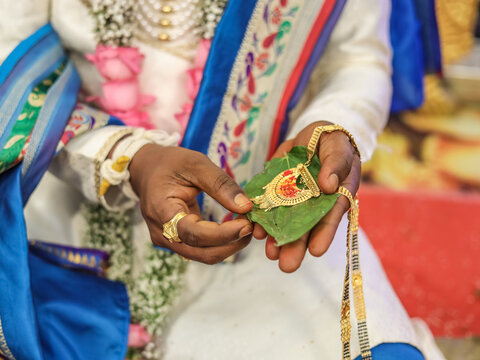 Groom Holding a Traditional Golden Mangalsutra on a Betel Leaf During an Indian Wedding Ritual, rich cultural heritage and emotional depth of Hindu wedding traditions.