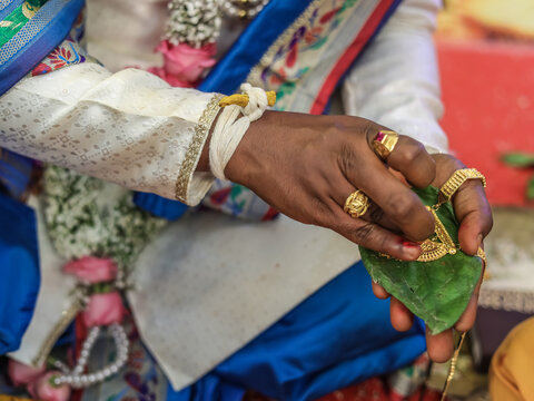 Groom's Hand Holding Betel Leaf and Gold Jewelry in Traditional Indian Wedding Ritual