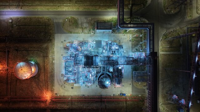 Aerial view of the illuminated industrial refinery in the South industrial zone at night, featuring complex piping, storage tanks, and bright lighting in Pancevo, Serbia.