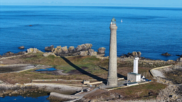 Aerial view of the Ile Vierge lighthouse standing on a rocky island surrounded by the blue sea in Plouguerneau, Bretagne, France.