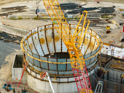 Aerial view of the American Fork wastewater treatment plant construction site featuring a large circular concrete and welded metal vat and a yellow crane in American Fork, Utah, United States.