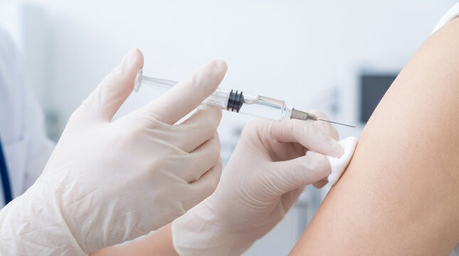 患者の二の腕に注射器で予防接種を行う医療スタッフの手元
