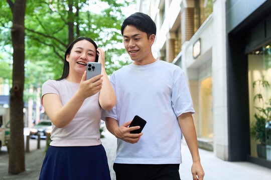 Young Japanese Man and Woman Walking on City Street with Smartphone