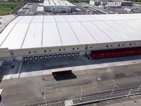 Aerial view of a large logistics center featuring extensive warehouse facilities, multiple loading docks, a parked trailer, and a paved yard in Santiago de Queretaro, Queretaro, Mexico.