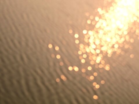 Abstract warm golden blurred of sunlight reflecting on water surface, creating shimmering bokeh lights. Ideal for backgrounds, concepts, or artistic projects