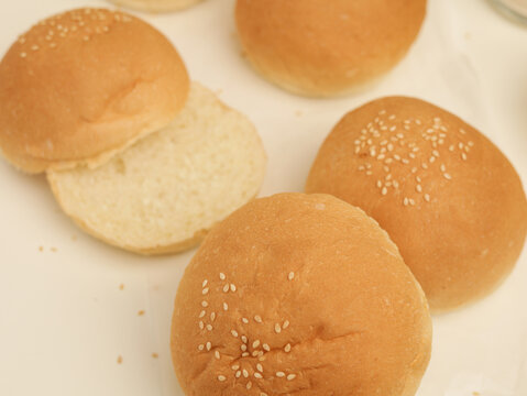 freshly baked sesame burger buns arranged on white parchment paper