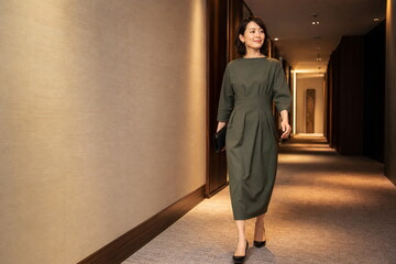 Fototapeta premium クラッチバッグを持ってホテル廊下を歩く女性