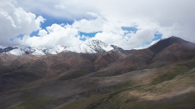 Drone view landscape of snow capped mountains with moving clouds and shadows on land in Ali, Tibet, China, 4k hyper lapse footage b roll shot travel concept.