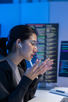 Developer woman programmer computer code office headset glasses screen technology developer woman working computer with code screen modern office, wearing glasses and wireless earbud Vertical