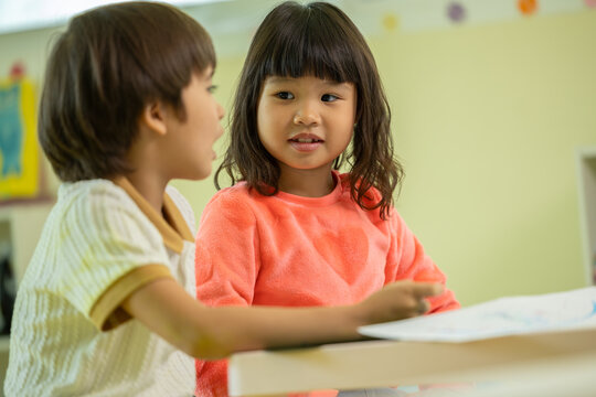 Asian child classroom learning friend desk conversation education preschool student school scene with young children sharing study time and calm interaction