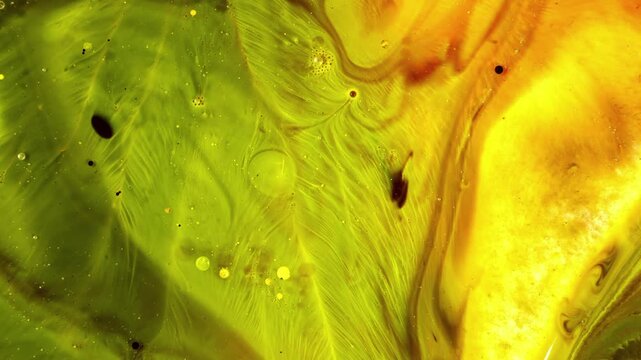 The dynamic movement of the liquid creates organic textures resembling leaves or feathers, accompanied by micro-bubbles and floating particles.
