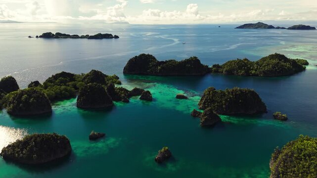 Aerial drone view of the iconic Piaynemo karst islands in Raja Ampat, Indonesia. Turquoise waters surround dramatic limestone formations and lush green islands, creating a spectacular tropical seascap