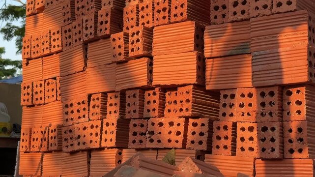 Stack of Red Perforated Clay Bricks at sunset. Construction Building Material Supply concept 