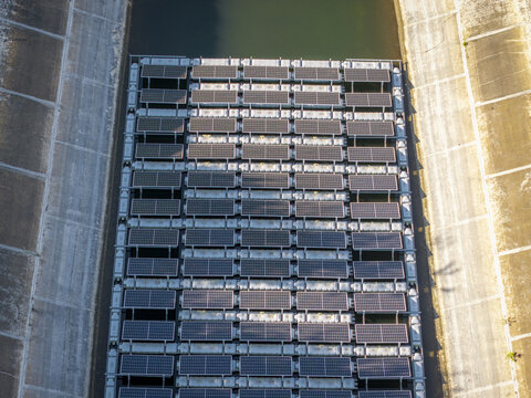 Aerial view of floating solar panels arranged in a grid on the water surface of a concrete canal in Poland.