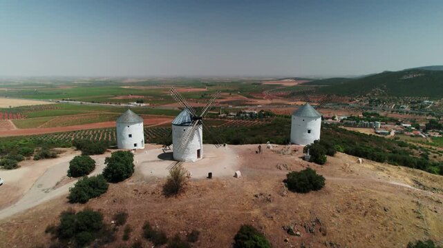 Traditional windmills dotting a dry landscape under a clear blue sky in rural spain