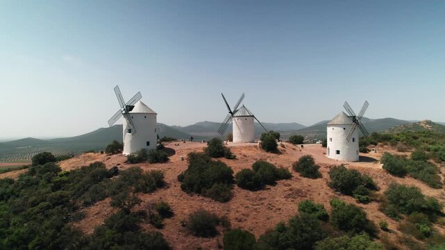 Traditional windmills dotting a dry landscape under a clear blue sky in rural spain