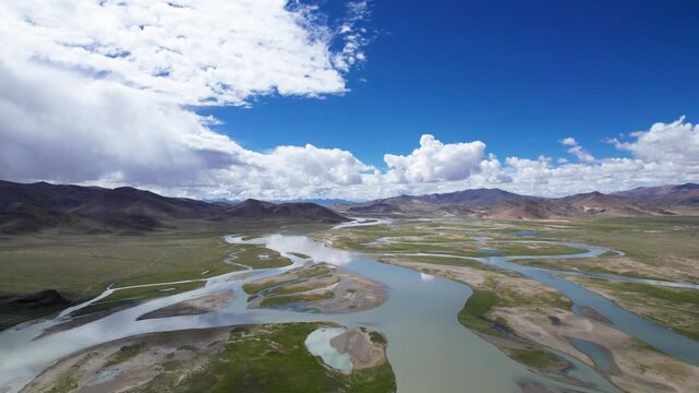 Drone view landscape of mountains and wetland rivers and lakes with blue sky and white clouds background and reflections in sunny day in Tibet, China, 4k real time footage b roll travel concept.