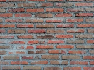 Fototapeta premium ​Rustic exposed red brick wall backdrop for architectural design, urban background, and construction graphic texture.