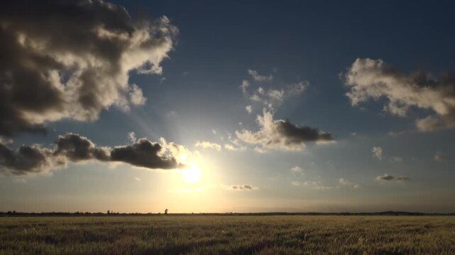 Sunset timelapse shows partly cloudy sky above flat plain as golden rays fade at horizon.