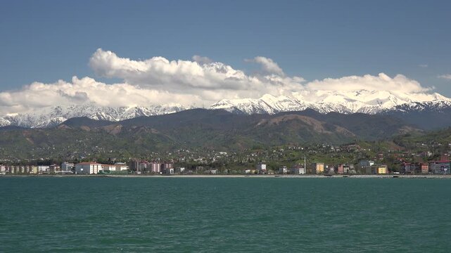 Rize Turkey Black Sea coastal city stands below snowy Pontic mountains and cloudy sky.
