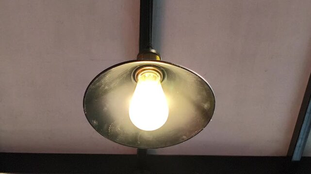 A vintage industrial pendant lamp featuring a dark metal dish-shaped shade and a warm LED filament bulb, creating a cozy retro ambiance for caf&eacute;s, restaurants, and interior spaces.