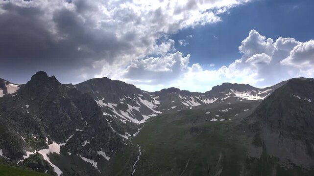 Anzer Rize Turkey valley shows snow patches, green meadows, clear stream, and rugged peaks.