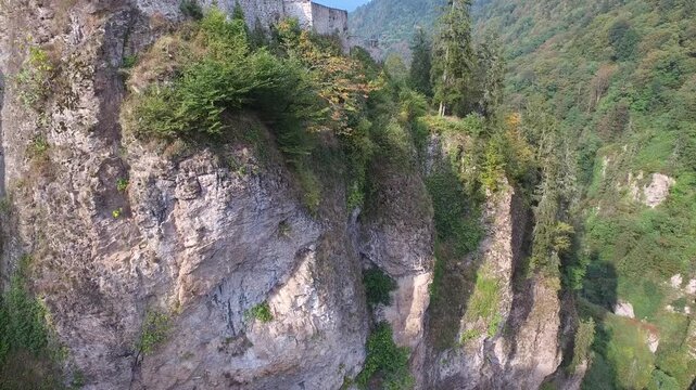 Aerial Zilkale fortress, Rize Turkey, above forested canyon and winding river under bright daylight.