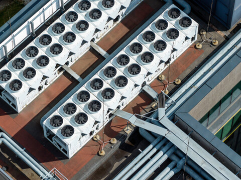 Aerial view of industrial cooling fans on a data center rooftop with metal piping and ventilation systems in Poland.