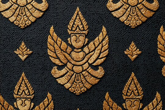Traditional Thai silk fabric with golden Thepanom angel pattern on black textured background