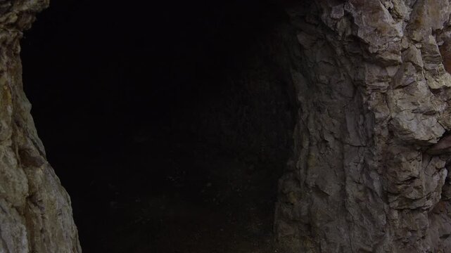 Mysterious dark cave interior revealing ancient rocky walls and shadowy underground chamber passage.