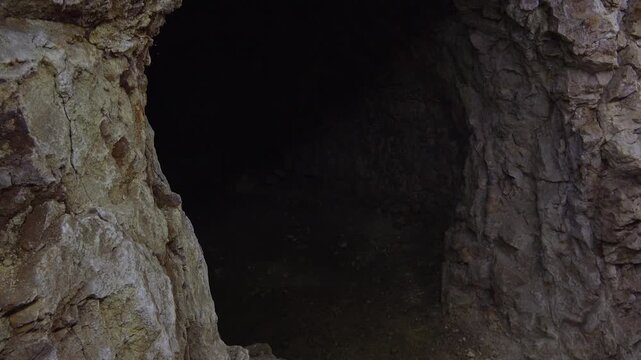 Mysterious dark cave interior revealing ancient rocky walls and shadowy underground chamber passage.