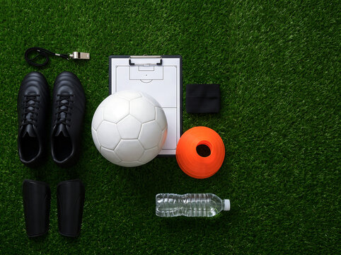 Top view of soccer training equipment arranged on green artificial grass surface.