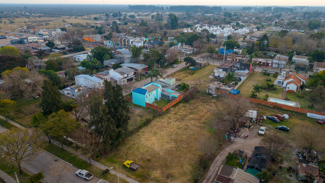 Aerial view of a residential neighborhood in San Jose de Feliciano featuring a bright blue house, surrounding trees, and streets in San Jose de Feliciano, Entre Rios Province, Argentina.