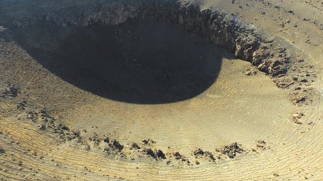Aerial drone massive sinkhole formed by underground collapse in barren desert plain.