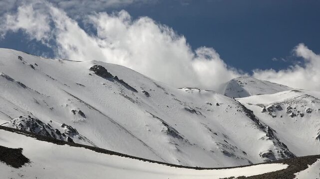 Timelapse warm clouds drifting above snow covered mountain ridges in spring in Antarctica.