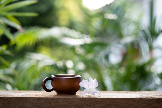 Simple wooden cup and pale purple orchid flower on wooden table