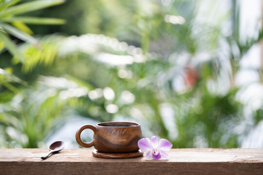 Wooden cup and purple orchid flower and spoon with lush green background