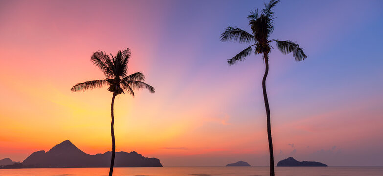 Vibrant Sunset Beach Silhouette with Palm Trees in Prachuap Khiri Khan,A breathtaking sunrise or sunset view over Ao Manao bay in Prachuap Khiri Khan, Thailand, featuring a scenic silhouette of two.