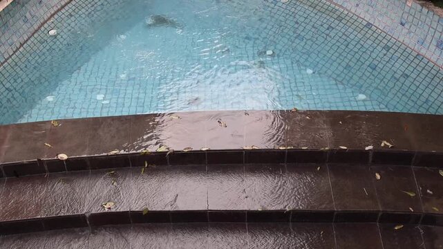 Swimming pool floor with blue mosaic tiles and abstract floral patterns visible beneath clear water. Aquatic texture, underwater geometric pattern, pool background, leisure facility detail