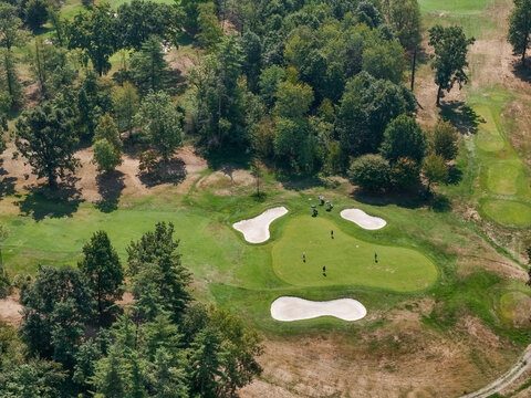 Aerial view of Golf Torino - La Mandria with golfers on the green surrounded by sand bunkers and lush trees in Fiano, Piemonte, Italy.