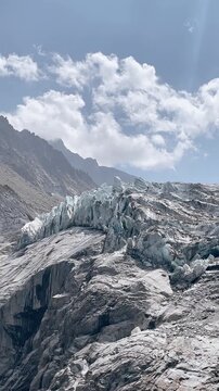 Majestic alpine glacier ice formations with rugged mountain peak background, vertical video 