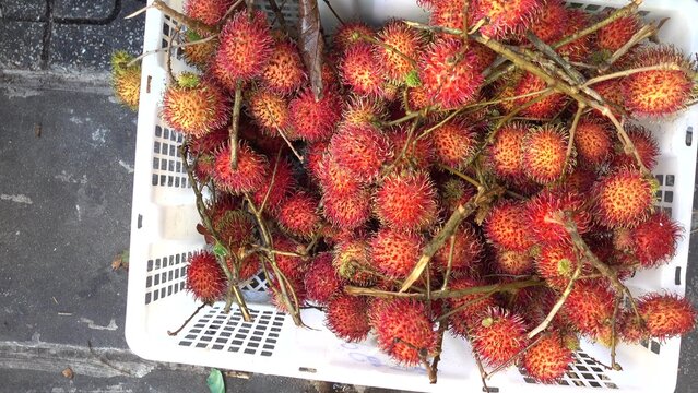 Fresh rambutan fruits in white plastic basket