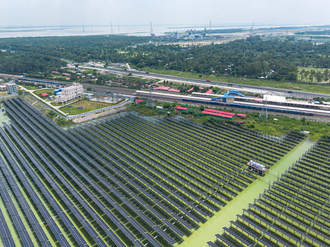 Aerial view of Sirajganj 68 MW Solar Park with rows of solar panels over water, adjacent to a railway line and station, Sirajganj, Rajshahi Division, Bangladesh.