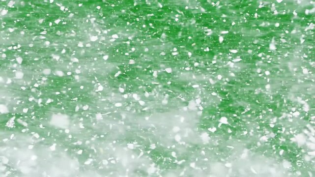 Heavy snow storm with swirling blizzard flakes and wind motion blowing across a solid chroma key green screen background