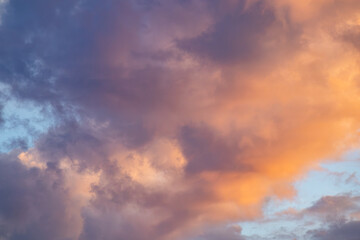 Obraz premium Dramatic sunset cloud formations illuminated by golden orange light against a deep blue sky