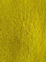 Macro close-up shot of vibrant yellow plush fabric texture, featuring soft fluffy microfiber fleece material for abstract background design. © MUHAMMAD