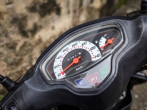Close-up shot of an analog scooter speedometer and fuel gauge panel showing odometer reading and fuel injection indicator.