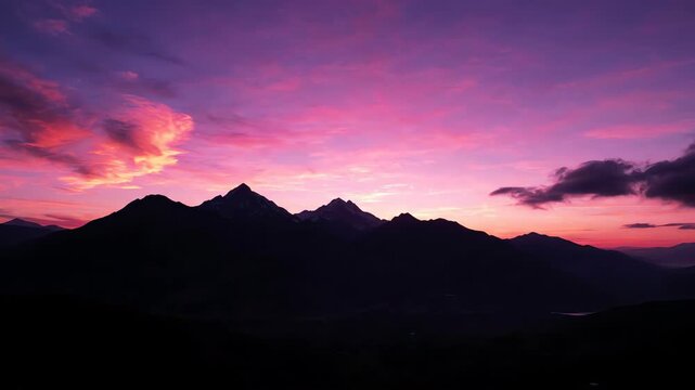 Ethereal silhouette of a mountain range under a vibrant pink and purple sunset sky with soft drifting clouds in a dreamy landscape