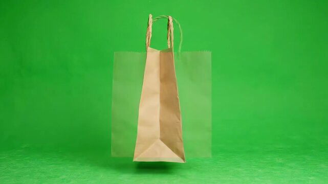 Isolated paper shopping bag floating and rotating against a bright green screen background for chroma key compositing