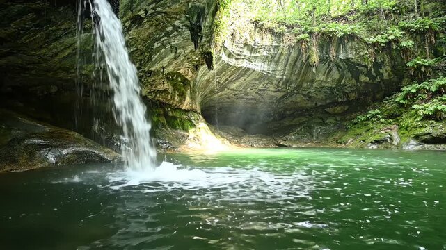 Minimalist close up shot of a waterfall cascading into the emerald green water of Hamilton Pool grotto in Texas